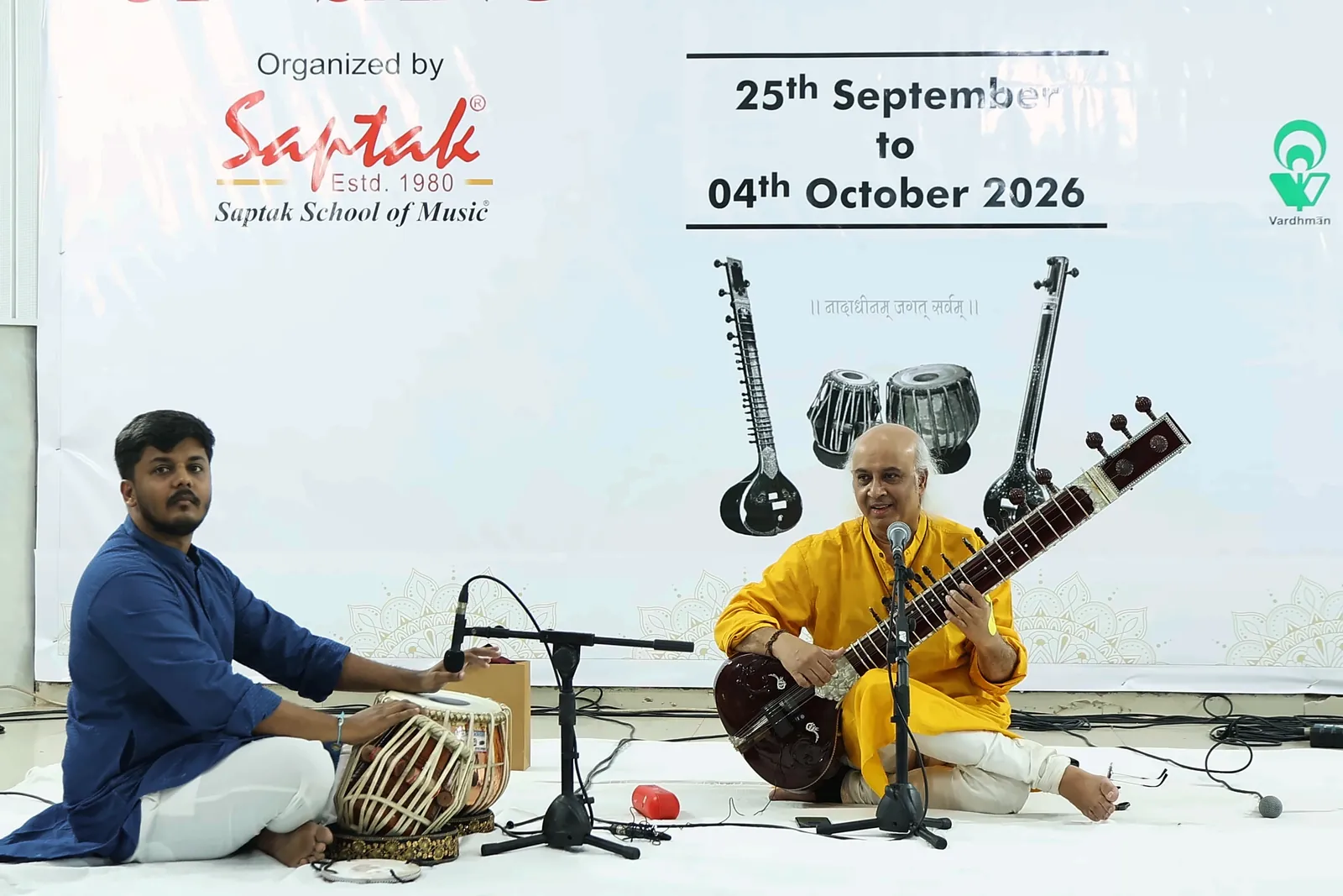 Riddhish Vora in a blue kurta playing tabla beside Vatsal Dave on sitar, with the festival dates 25th September to 04th October 2026 on the banner behind them