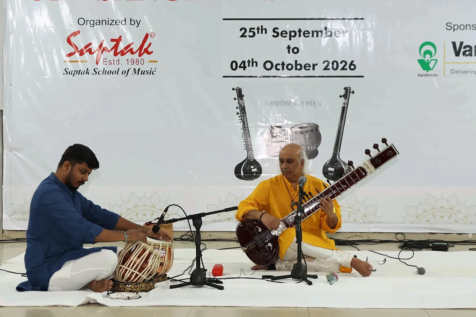 Riddhish Vora on tabla and Vatsal Dave on sitar performing together under the Saptak School of Music logo and festival dates